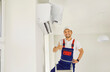© Studio Romantic - Portrait of smiling male technician in work uniform showing thumb up after commissioning air conditioner. Concept of installation, repair and maintenance services of indoor unit of air conditioner