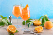 © Anna Fedorova - Classic italian aperitif aperol spritz cocktail in two wineglasses with ice cubes and slice of orange with light blue background on beige stone background, traditional summer fresh iced drink, closeup