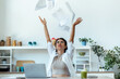 Worried woman tossing invoices and documents into the air while working on the laptop at home.