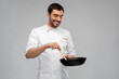 © Syda Productions - food cooking, culinary and people concept - happy smiling male chef in jacket with frying pan and spoon over grey background