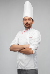 Wall Mural - cooking, culinary and people concept - male chef in toque and jacket with crossed arms over grey background