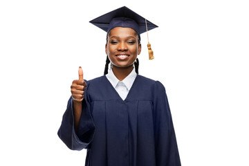 Wall Mural - education, graduation and people concept - happy graduate student woman in mortarboard and bachelor gown showing thumbs up