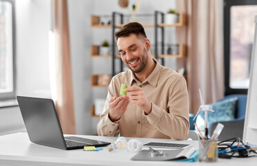 Canvas Print - distance education, school and green energy concept - happy smiling male teacher with laptop computer and alkaline battery having online class at home office