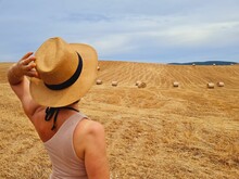 Back View Of A Woman With A Straw Hat In A Harvested Wheat Field