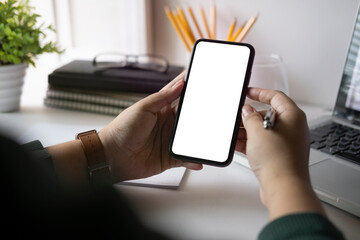 Wall Mural - view over shoulder of woman hands holding smart phone. empty screen for your advertise text.