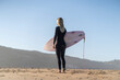 Surfer girl at the beach standing with her surfboard in the morning. Female surfer