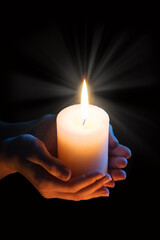 Women's hands holding a candle