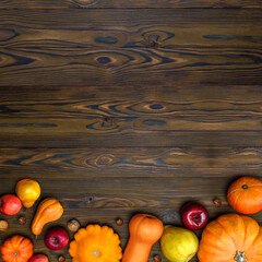 Wall Mural - Thanksgiving day pumpkin harvest on a wooden background with empty copy space. Squash, orange vegetable autumn fruit, apples, nuts on a wooden table for traditional Halloween decoration fall design