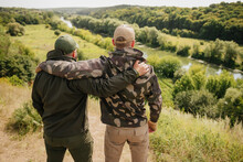 Two guys hunters fishers wearing tactical hunter gear happy meet each other and enjoy nice natural outdoor landscape