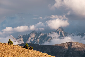 Wall Mural - Dark clouds over the craggy mountain peaks of Punta Cavallare, Pinzi a i Giuelli and Turone lit by evening sunlight in Corsica