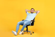 © New Africa - Young man relaxing in comfortable office chair on yellow background