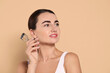 © New Africa - Woman with eyelash curler on beige background. Space for text