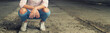 Detail of young girl crouching in torn jeans and sneakers