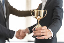 The Hands Of An Employee Receiving A Golden Cup Reward From The Company Manager Represent His Performance In His Career Job Reward.