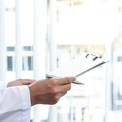 Wall Mural - Doctor uses a laptop computer to record patient information and write it on a document to prepare for diagnosis in the room of a modern hospital, Emergency assistance and health care concept.