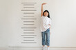 © kongga studio - Kid is measuring the growth on the background of wall. Girl power concept.