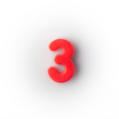 Plastic magnetic number 3 three red on a white background top view.