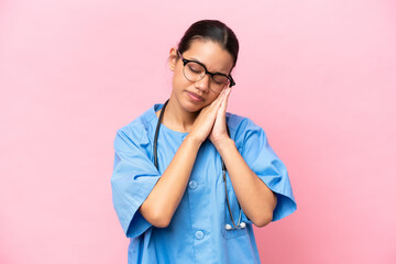 Young nurse Colombian woman isolated on pink background making sleep gesture in dorable expression