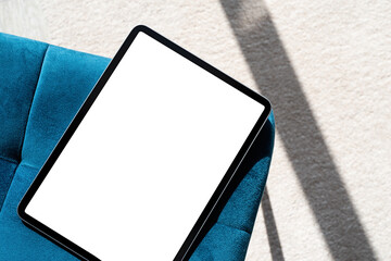 digital tablet computer with isolated screen on blue chair. at home interior.