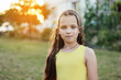 © Andriy Medvediuk - front view of adorable little girl with hairstyle is smiling with her outdoors on summer day. caucasian friendly and shy kid looking at camera posing. Happy childhood on holiday vacation