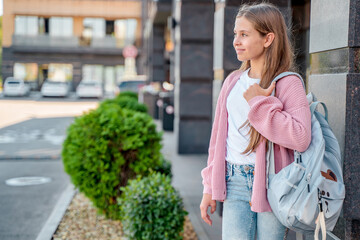 A young teenage girl goes to school with a backpack. A teenage student or a schoolgirl. The concept of education. Happy girl's face, positive and smiling emotions.