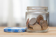 An Open Jar With Small Coins Of American Cents Stands On A Wooden Table, Top View, Close-up, Selective Focus. A Concept For Business And Finance, Savings And Price Increases.