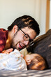 © Austockphoto - Father smiling and interacting with baby in morning sunlight on bed