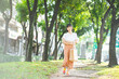 © dodotone - Young adult southeast business asian woman walking on footpath public park outdoor break in city.