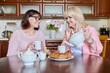 © Valerii Honcharuk - Friends two mature women drinking tea with cupcake in kitchen