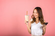 Asian beautiful young woman holding drinking brown sugar flavored tapioca pearl bubble milk tea and mobile phone, Portrait female, studio shot isolated on pink background, milk beverage concept