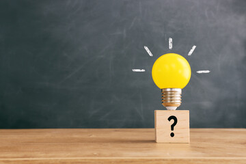 Wall Mural - Yellow bright light bulb and question mark over blackboard background
