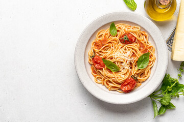 Spaghetti pasta with tomatoes and basil in ceramic plate on white background. Traditional Italian pasta with tomato sauce. Mediterranean cuisine