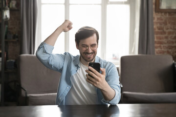 Wall Mural - overjoyed mobile phone user man looking at screen with happy smile, reading notice, text message, ge