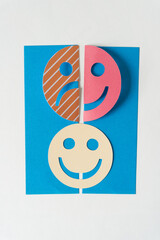 Wall Mural - happy-sad smiley and bright smiley on blue paper