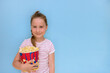 © Елена Белоусова - little girl with a big glass of popcorn on a blue background with copy space