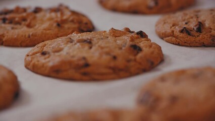 Sticker - Close-up shot of freshly baked chocolate chip cookies on white table, slow motion