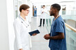 © Seventyfour - Side view portrait of female doctor talking to assistant while standing in hall of modern clinic