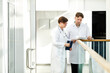 © Seventyfour - Minimal portrait of two expert doctors discussing case in hall of modern clinic in white tones, copy space