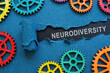 The inscription neurodiversity under the torn paper and gear wheels.