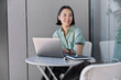 © wayhome.studio  - Intelligent female student of university searches information for course work uses modern laptop device looks thoughtfully away poses at small table with notebooks and takeaway coffee checks database