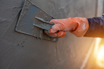 Close-up shot of a cement worker using a trowel to plaster the walls