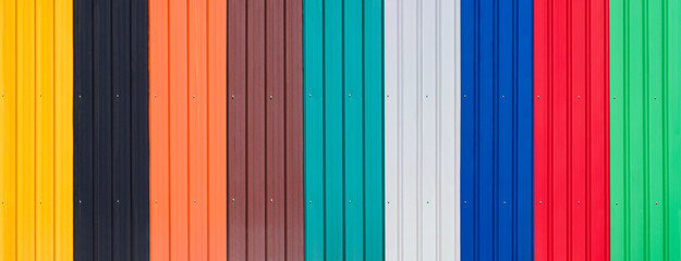 Background of multicolored corrugated metal sheets with polymer coating for wall and roofing in panoramic view