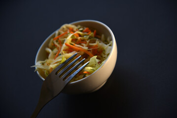 Wall Mural - Delicious salad of vegetables and sauces in a salad bowl with a fork. Salad on a black background.