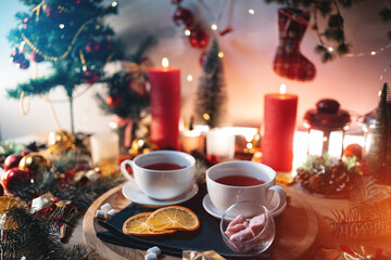 two cups of black or berry red hot english christmas tea with decor and candle