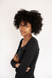 © KAMPUS - Portrait of smiling African American woman looking at camera. Young female model wearing black dress posing against white background. Female beauty concept