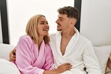 Fototapeta  - Young caucasian couple smiling happy and hugging on the bed at home.