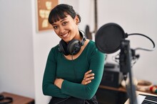 Young Beautiful Hispanic Woman Musician Smiling Confident Sitting With Arms Crossed Gesture At Music Studio