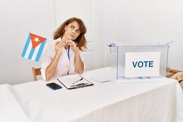 Sticker - Beautiful caucasian woman at political campaign election holding cuba flag serious face thinking about question with hand on chin, thoughtful about confusing idea