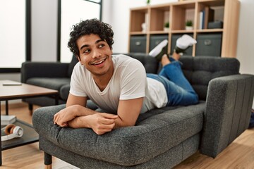 Poster - Young hispanic man smiling happy lying on the sofa at home.