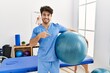 © Krakenimages.com - Hispanic physiotherapy man working at pain recovery clinic smiling happy pointing with hand and finger